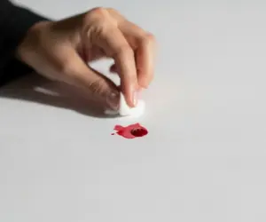 لکه خون روی پارچه سفید و دست زنی ایرانی در حال پاک کردن آن - روش‌های از بین بردن لکه خون