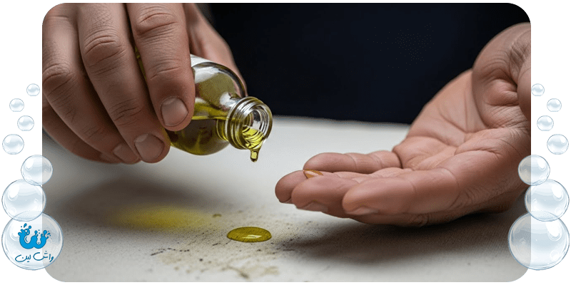 دست‌های مردی ایرانی در حال ریختن روغن زیتون روی لکه قیر روی پارچه برای نرم کردن و حل کردن قیر.