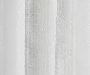 تصویر ماکرو از یک پرده نازک و تمیز که قطرات آب روی آن می‌درخشد، نماد شستشوی پرده.