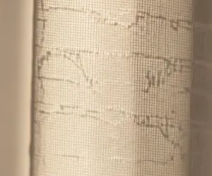 نمای نزدیک از بافت تمیز و شفاف پرده حریر با عبور نور؛ نماد لطافت و پاکیزگی پس از شستشوی حرفه‌ای منسوجات.