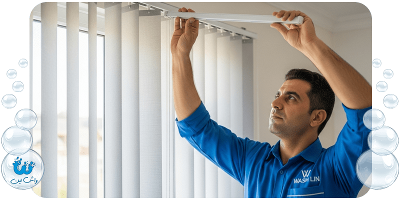 متخصص خشکشویی واش‌لین با یونیفرم و لوگوی واش‌لین در حال نصب پرده لوردراپه تمیز شده.