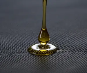 نمای نزدیک از لحظه برخورد قطره روغن با پارچه کت؛ شروع چالش لکه چربی و نیاز به راهکار سریع نظافت.