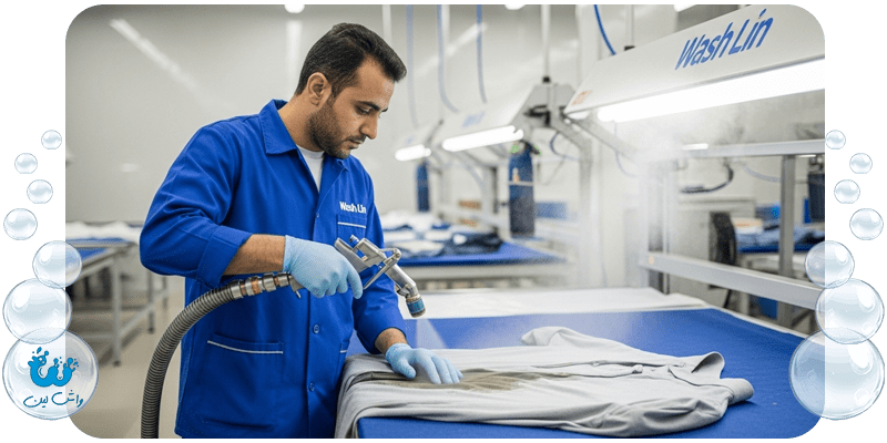 متخصص خشکشویی واشلین در حال استفاده از گان بخار برای لکه‌بری تخصصی انواع لباس.