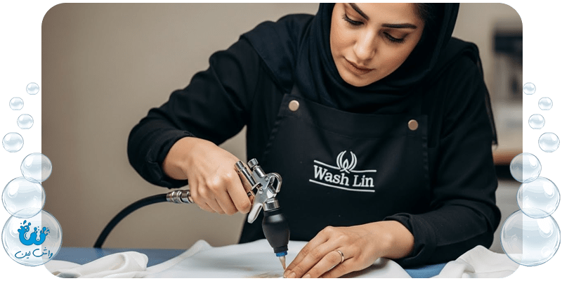 متخصص لکه‌بری در حال پاک کردن لکه از روی لباس ابریشمی با دستگاه مخصوص