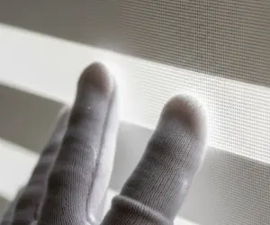 نمای نزدیک از بافت تمیز پرده زبرا و دستکش سفید متخصص کنترل کیفیت